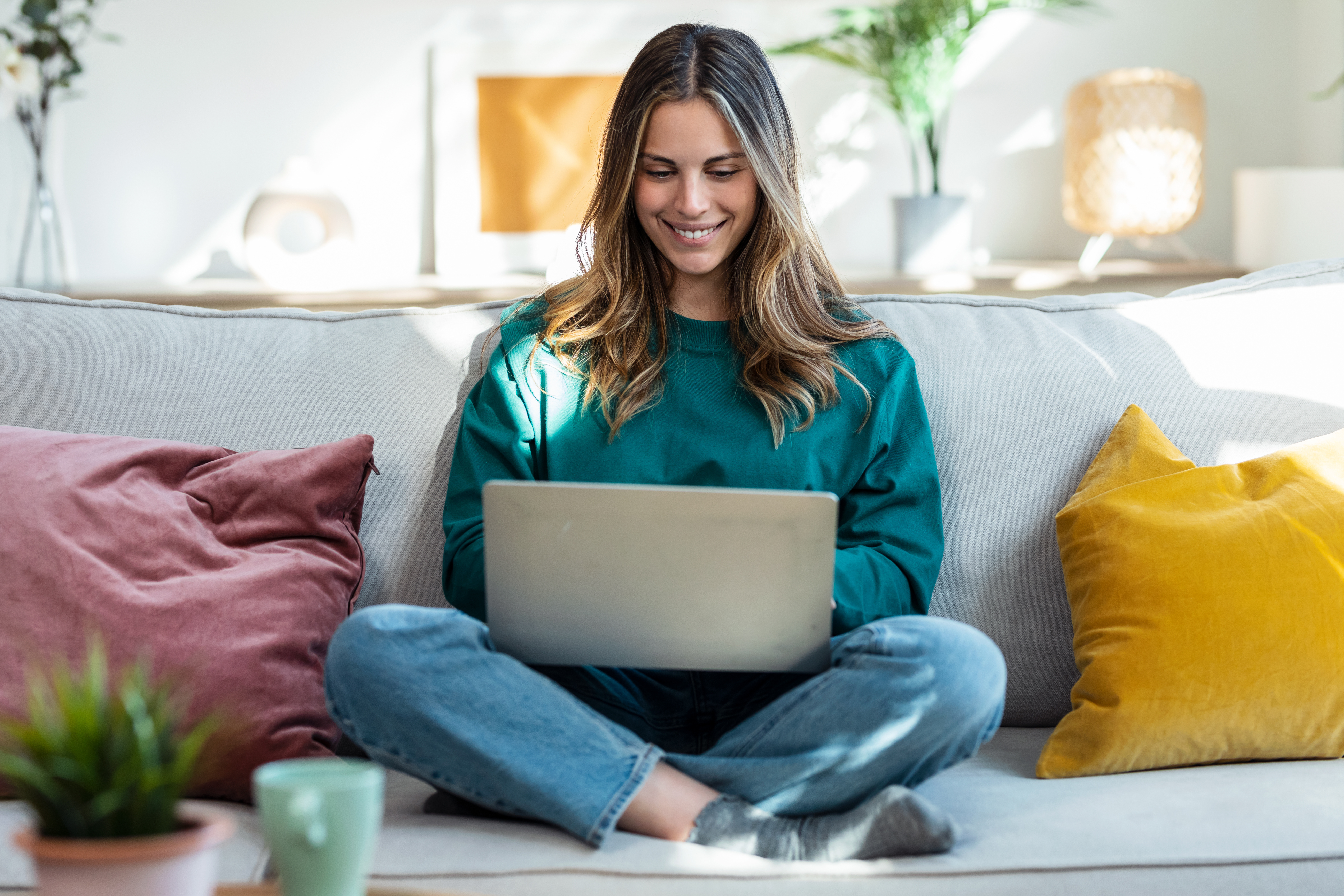 A young woman researches credit union checking accounts on her couch.
