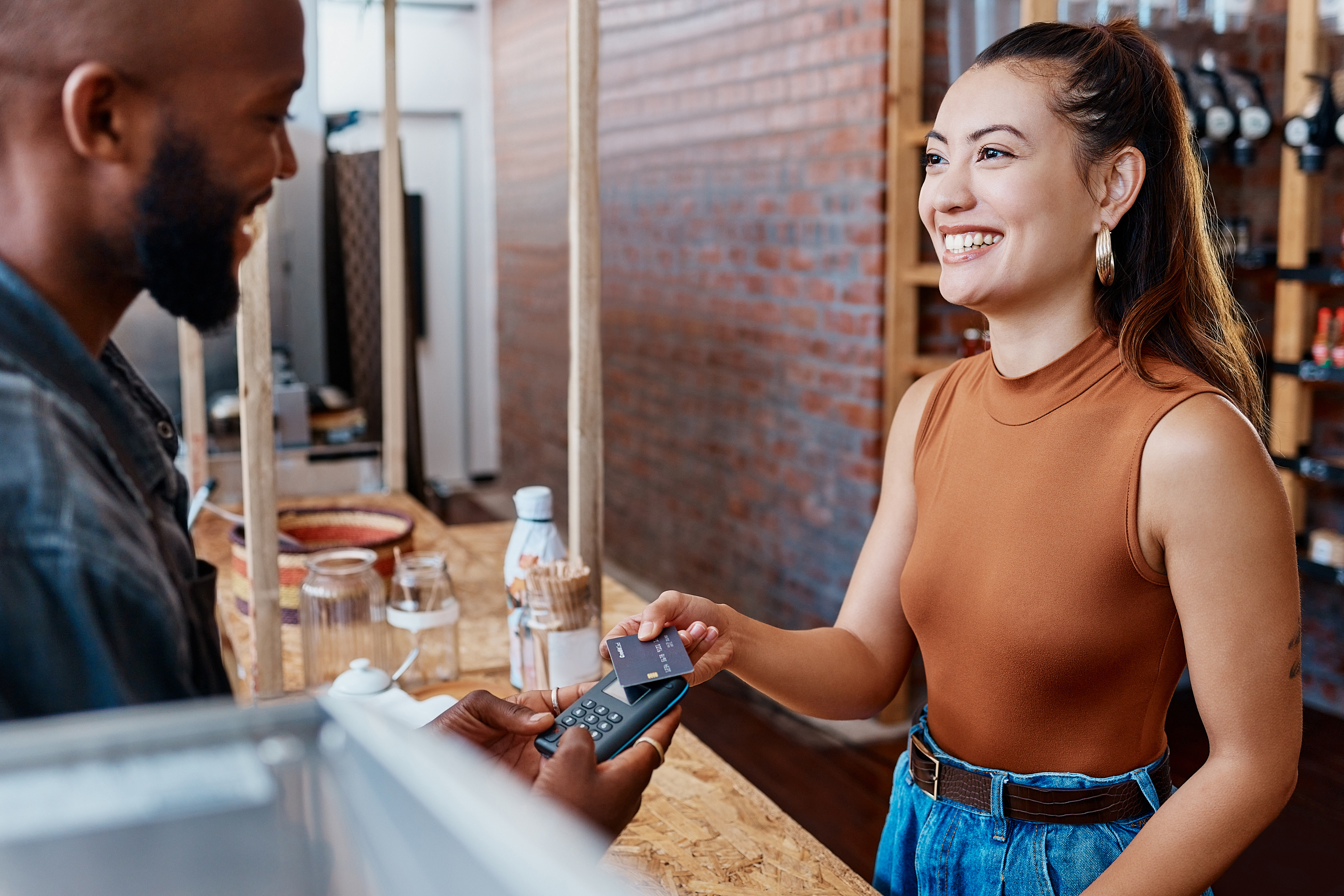 A woman makes a contactless payment at a cafe with her debit card.