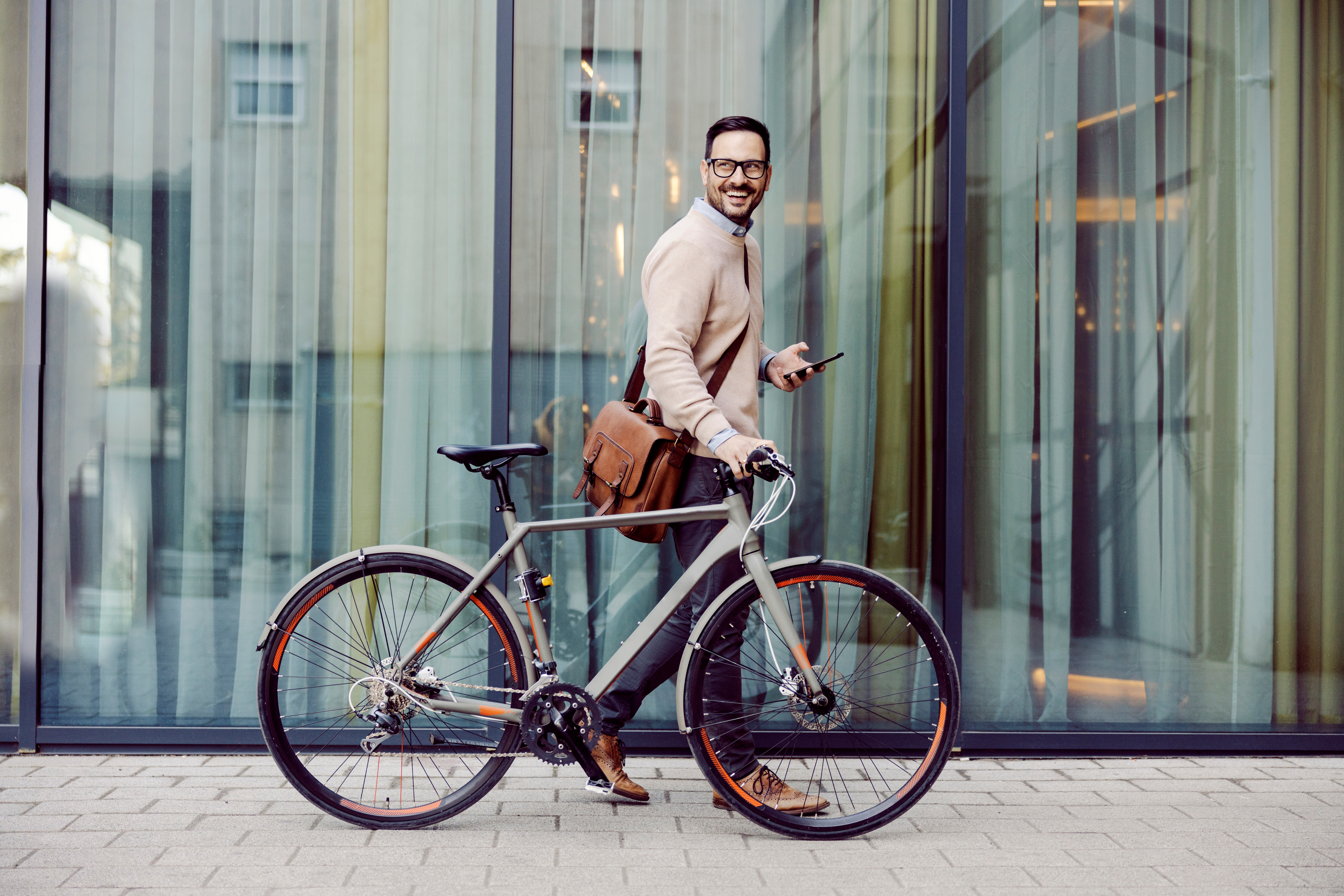 A man walks his bike to work in the city.